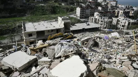 A damaged excavator sits on the rubble of a building that was hit in January by an Israeli strike in the southern Lebanese village of Qannarit, on February 16, 2026. Despite a November 2024 truce that sought to end more than a year of hostilities between Israel and Hezbollah, Israel has kept up regular strikes on Lebanon, usually saying it is targeting the Iran-backed group. (Photo by Joseph EID / AFP)