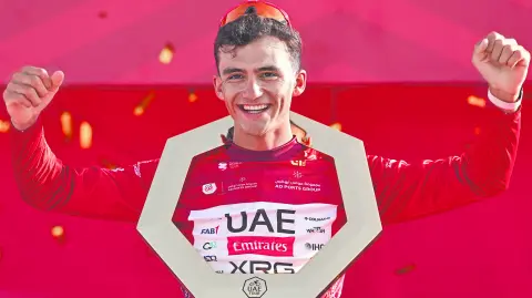 Championship first place winner UAE Team Emirates's Mexican rider Isaac Del Toro Romero celebrates with the trophy on the podium after the seventh and final stage of the UAE Tour cycling event from Zayed National Museum to Abu Dhabi Breakwater in Abu Dhabi on February 22, 2026. (Photo by Fadel SENNA / AFP)