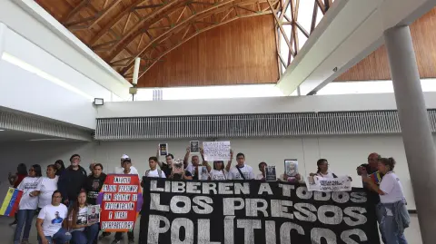 Relatives of a political prisoners hold banners after a press conference in Caracas on February 23, 2026. More than 200 Venezuelan political prisoners were on hunger strike on February 22, 2026, to demand their release under a new amnesty law that excludes many of them. (Photo by Pedro MATTEY / AFP)