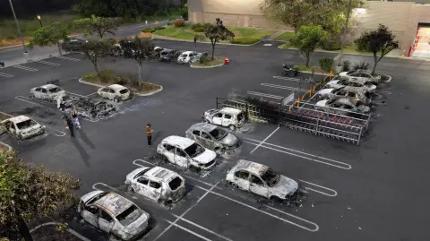 Aerial view of burned cars in the parking lot of a Costco retail store in Puerto Vallarta, Jalisco state, Mexico, on February 23, 2026. Mexico has deployed 10,000 troops to quell clashes sparked by the killing of the country's most wanted drug lord, which have left dozens dead, officials said on February 23. Nemesio "El Mencho" Oseguera, leader of the Jalisco New Generation Cartel (CJNG), was wounded on February 22 in a shootout with soldiers in the town of Tapalpa in Jalisco state and died while being flown to Mexico City, the army said. (Photo by Alfredo ESTRELLA / AFP)