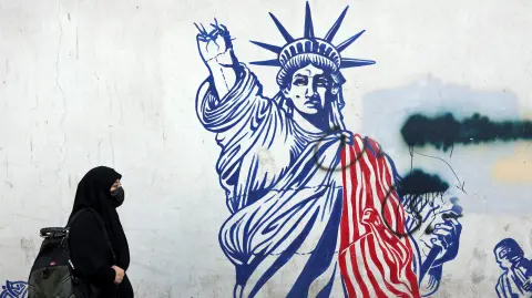 Una mujer iraní con velo camina frente a un mural antiestadounidense junto a la antigua embajada de Estados Unidos en Teherán.
