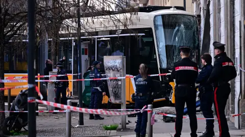 Italian police officers stand at the site of a tram derailment in Milan on February 27, 2026. A tram derailed and smashed into a building in Milan on February 27, 2026, killing one person and injuring around 20 others, the police told AFP. (Photo by Piero CRUCIATTI / AFP)