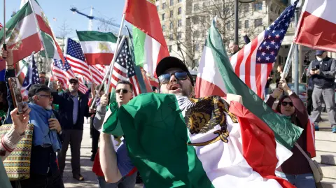 People cheer and wave Iranian and US flags during a rally expressing support for US and Israeli military action against Irans Islamic Republic government on February 28, 2026 in Washington, DC. The US and Israel launched an attack of unprecedented scale against Iran on Saturday, reportedly killing more than 200 people, with Tehran launching a retaliatory missile barrage that sent people running for cover across the Middle East. (Photo by Amid FARAHI / AFP)