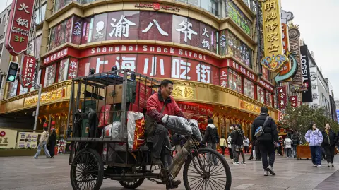 A man rides a tricycle on the Nanjing Road Pedestrian Street in Shanghai on March 4, 2026. (Photo by Jade GAO / AFP)