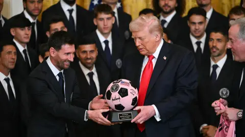 Argntinian star Lionel Messi hands US President Donald Trump a ball during an event for Inter Miami CF, winners of the 2025 Major League Soccer Cup, in the East Room of the White House in Washington, DC, on March 5, 2026. (Photo by ANDREW CABALLERO-REYNOLDS / AFP)