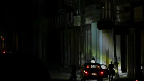 A car parks on a dark street during a blackout in Havana on March 4, 2026. (Photo by Yamil LAGE / AFP)