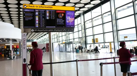 FILE PHOTO: Qatar airline staff stand by a departure board displaying cancelled flights to Middle East countries amid the U.S.-Israel conflict with Iran, at Heathrow Airport Terminal 4, in Greater London, Britain, March 2, 2026. REUTERS/Isabel Infantes/File Photo