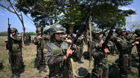 Members of the Guatemalan Army Parachute Brigade handle their weapons after performing a tactical parachuting exhibition in Puerto San Jose, Escuintla department, Guatemala, on April 30, 2025. (Photo by JOHAN ORDONEZ / AFP)