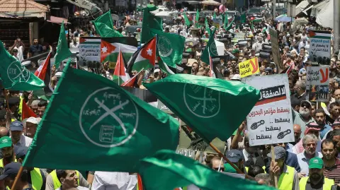 Flags of the Muslim Brotherhood, Jordan, and other political parties are waved with other protest signs denouncing the US-led Middle East economic conference in Bahrain, during a post-Friday prayers demonstration against US President Donald Trump's "Deal of the Century" in the Jordanian capital Amman on June 21, 2019. (Photo by Khalil MAZRAAWI / AFP)