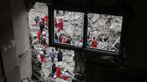 Personal de emergencia trabaja entre los restos de un edificio residencial atacado en Teherán.