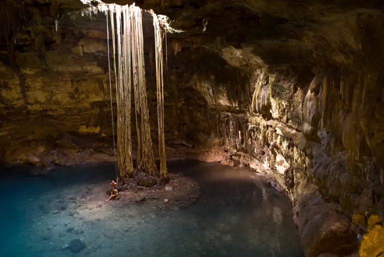 Cenote Samula, famoso por la luz que se filtra desde la abertura en la bóveda, iluminando sus aguas turquesas y raíces colgantes.